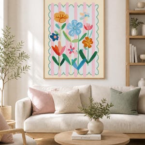 May include: A framed floral art print with vibrant flowers set against a pink and white striped backdrop. The artwork hangs above a cream sofa with cushions. A wooden coffee table, holding a vase and a book, sits in front of the sofa.