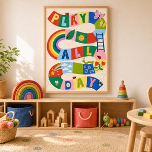 Op de afbeelding: Een rechthoekige wandkunstprint met een kleurrijk kronkelend pad met de tekst PLAY ALL DAY. Het ontwerp bevat illustraties van een regenboog, zon, ladder, bloemen, lieveheersbeestjes, bijen en een rups op een crèmekleurige achtergrond.