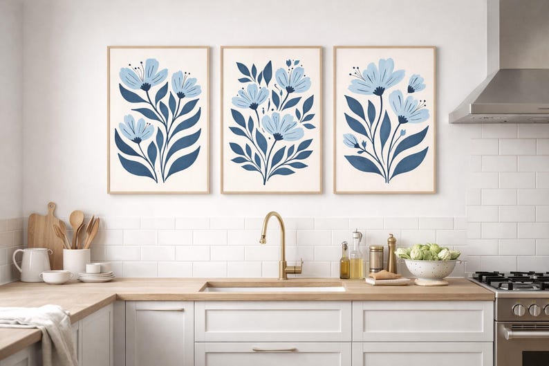 Puede incluir: Tres impresiones art&iacute;sticas florales enmarcadas. Cada impresi&oacute;n presenta un dise&ntilde;o de flores azul claro con hojas y tallos azul oscuro sobre un fondo crema. Los marcos son de color madera clara. Las impresiones se exhiben en una cocina.