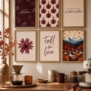 Puede incluir: Seis láminas decorativas enmarcadas con motivos otoñales, incluyendo calabazas, una flor y paisajes de montaña con el texto Hello Autumn, everything's better in sweater weather y Fall in love, expuestas sobre una encimera de madera.