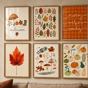 Può includere: Un set di sei stampe artistiche da parete incorniciate a tema autunnale. Le stampe mostrano illustrazioni di fogliame autunnale, vari funghi, zucche, zucchine, un ombrello e stivali, con il testo 'tis the season to be autumn' e 'cozy vibes only'.