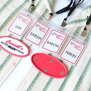 Puede incluir: Cuatro tarjetas de identificación rectangulares con cordones negros, cada una con el texto Cassell's Music y un nombre: Ian, Sarah, Baron o Nikki. Se incluyen dos soportes magnéticos ovalados de color rosa, uno con el logo de Cassell's Music.