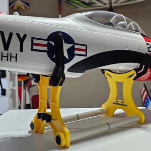 K&ouml;nnte beinhalten: Ein gelber und wei&szlig;er Flugzeugst&auml;nder mit einem wei&szlig;en Flugzeug darauf. Das Flugzeug ist mit den Worten "NAVY VT-HH" und der Nummer "217" bemalt.