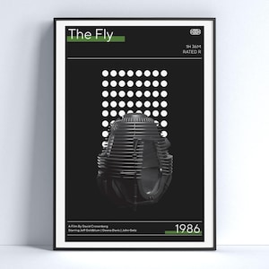 Op de afbeelding: Een ingelijste poster voor de film "The Fly", met een zwart-wit ontwerp en groene accenten. De poster toont een gestileerde afbeelding van een vliegenkop en het jaar 1986. Verkrijgbaar in verschillende formaten, waaronder 10 cm x 15 cm en 50 cm x 75 cm. De tekst "Printable as 2:3 Aspect Ratio" is zichtbaar.