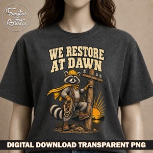 Puede incluir: Una camiseta gris carbón con el gráfico de un mapache que lleva un casco amarillo, una capa y botas de trabajo, de pie junto a un poste eléctrico. El texto "WE RESTORE AT DAWN" está impreso sobre el mapache en una fuente clara y negrita.