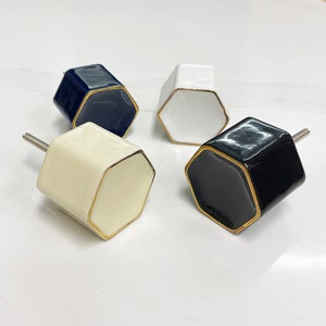 May include: Four hexagonal ceramic cabinet knobs with gold trim. The knobs are in white, black, and navy blue.