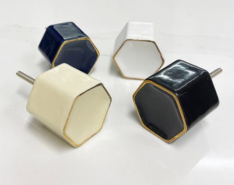 Pomos hexagonales de cerámica para puertas de armario con detalles dorados. Aptos para puertas de armario de hasta 30 mm de grosor. Disponibles en negro, azul, crema y blanco.