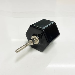 May include: Black hexagonal ceramic cabinet knob with a silver screw.