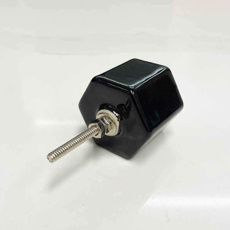 May include: Black hexagonal ceramic cabinet knob with a silver screw.
