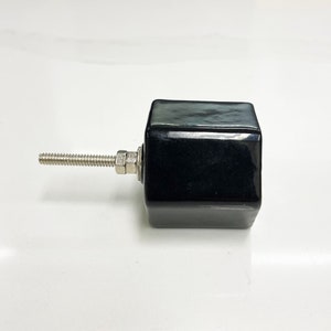 May include: Black ceramic cabinet knob with a hexagonal shape and a silver screw.