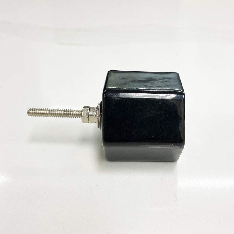 May include: Black ceramic cabinet knob with a hexagonal shape and a silver screw.