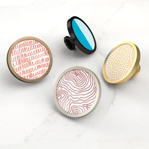 Può includere: Quattro pomelli decorativi per mobili con design unici. Uno presenta un motivo rosso a scarabocchi, un altro un design a mappa topografica, un terzo un motivo a strisce blu e bianche e l'ultimo un motivo a pois gialli.