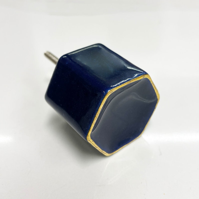 May include: A dark blue hexagonal ceramic cabinet knob with a gold trim.