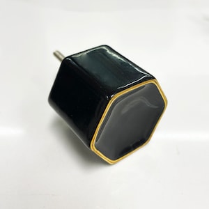 May include: Black hexagonal cabinet knob with a gold trim.
