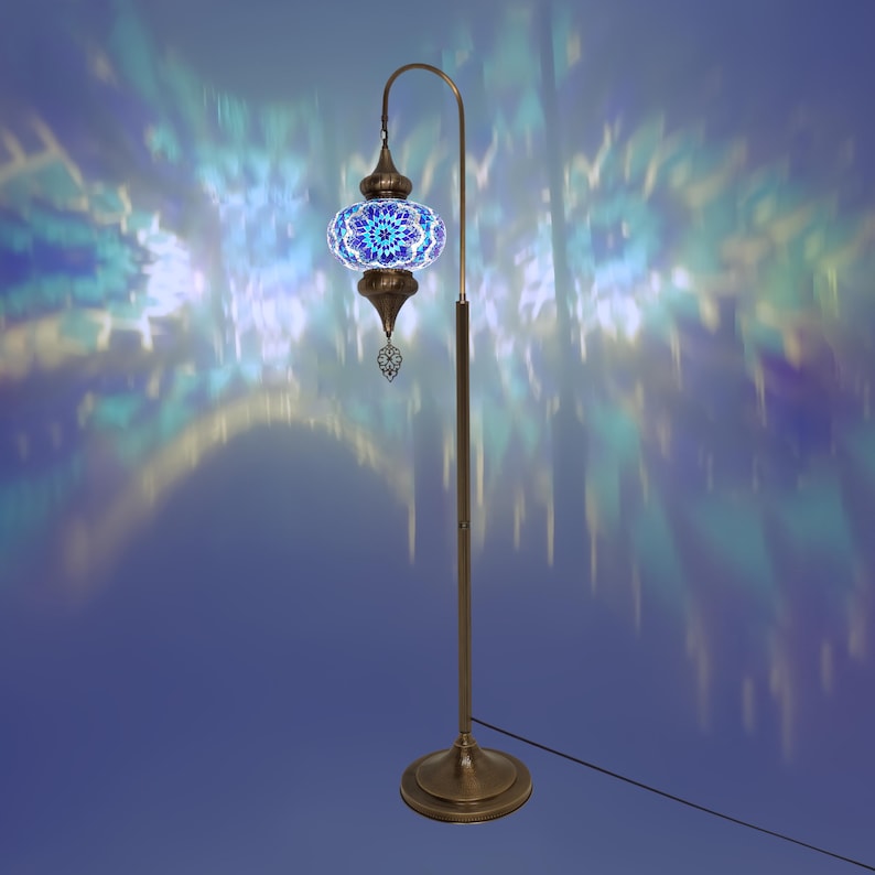 May include: A floor lamp with a blue and gold mosaic glass shade. The lamp has a curved arm and a round base. The shade casts a colorful pattern on the wall behind it.