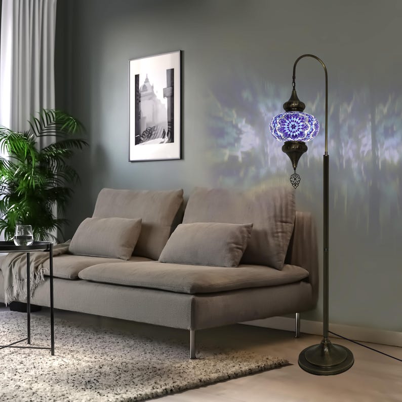 May include: A blue and white mosaic glass floor lamp with a curved arm and a decorative finial. The lamp is on a gray rug in a living room setting.
