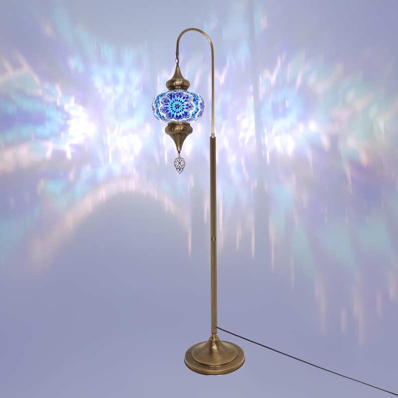 May include: A floor lamp with a blue and white mosaic glass shade. The lamp has a brass base and a curved arm.