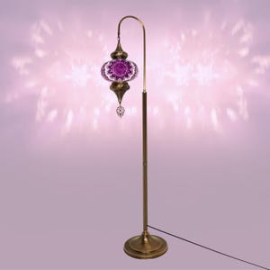 May include: A floor lamp with a purple mosaic glass shade and a brass base. The lamp has a curved arm and a decorative finial.