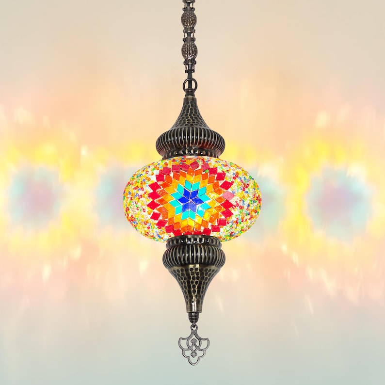 K&ouml;nnte beinhalten: Eine farbenfrohe Pendelleuchte im Mosaikstil mit Sternmuster. Die Lampe verf&uuml;gt &uuml;ber eine lebendige Anordnung aus roten, orangen, gelben, gr&uuml;nen und blauen Glasteilen. Der Metallrahmen hat eine antike Bronze-Oberfl&auml;che und die Lampe h&auml;ngt an einer Kette.