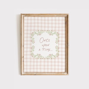 Peut inclure: Impression encadrée avec un cadre en bois brun clair. L'impression présente un fond à carreaux beige et blanc. Au centre, une couronne florale entoure les mots "Once upon a time..." dans un style manuscrit.