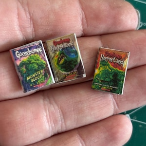 Puede incluir: Tres libros de bolsillo en miniatura de Goosebumps y Goosebumps Horrorland. Los libros de Goosebumps son verdes, amarillos y rojos con el título "Goosebumps" y el título del libro "Monster Blood". Los libros de Goosebumps Horrorland son amarillos y rojos con el título "Goosebumps Horrorland" y el título del libro "The Creature from the Black Lagoon".