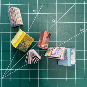 Puede incluir: Una colección de libros en miniatura con portadas coloridas. Los libros incluyen títulos como "Peanut Butter & Celery", "Magic Tree House" y "La historia de Babar".