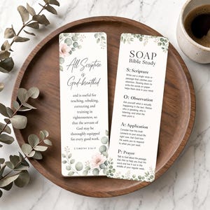 May include: Two rectangular bookmarks with floral accents and text. One bookmark reads "All Scripture is God-breathed." The other reads "SOAP Bible Study" with instructions. The bookmarks are on a wooden tray with a cup of coffee.