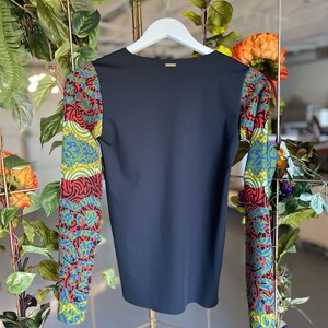 May include: Black long-sleeve shirt with colorful patterned sleeves. The sleeves feature a geometric design with red, green, blue, and yellow colors.