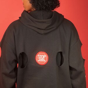 May include: Black hoodie with a red "STOP GLOBAL WARMING" patch on the back. The hoodie has two large holes on the back.