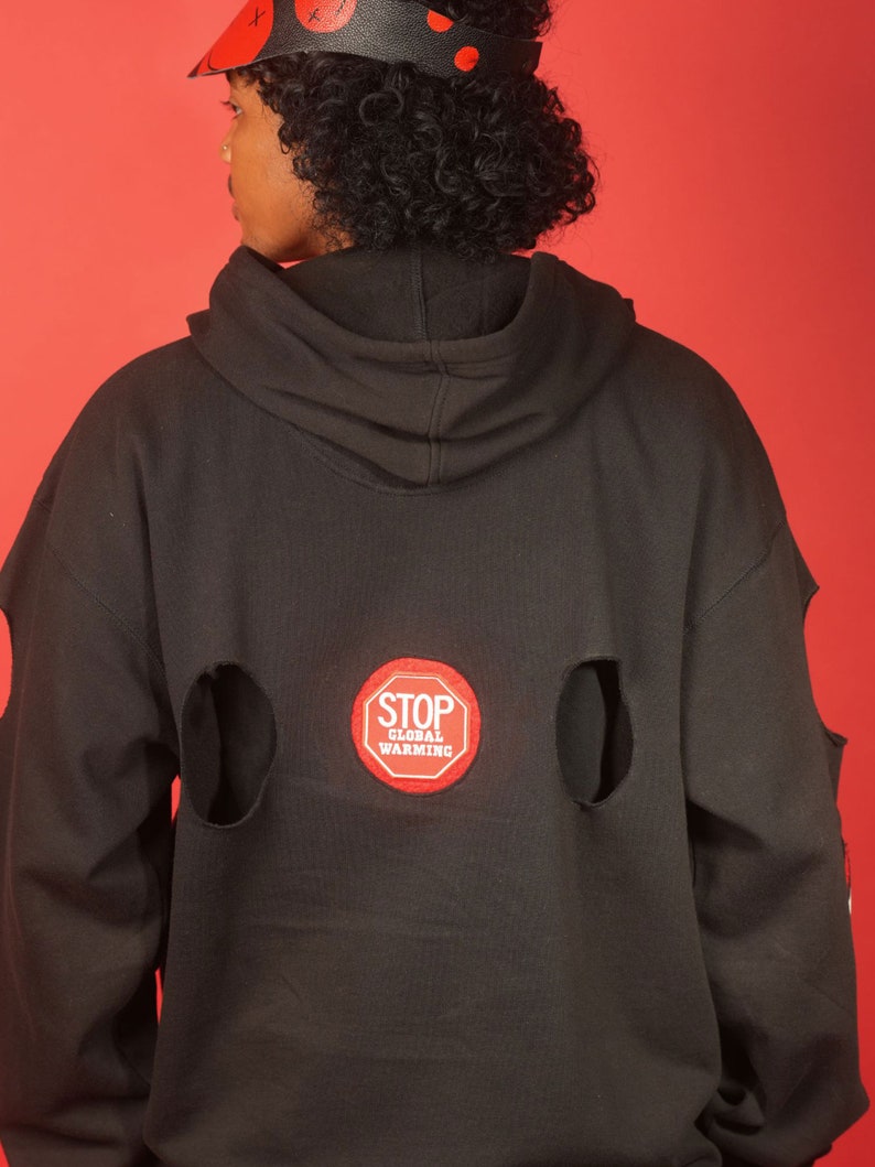 May include: Black hoodie with a red "STOP GLOBAL WARMING" patch on the back. The hoodie has two large holes on the back.