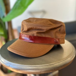 Discover our transformable hat, crafted from organic cotton and accompanied by an up-cycled leather pin.
