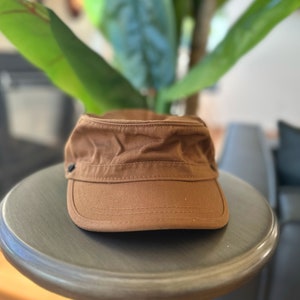 Discover our transformable hat, crafted from organic cotton and accompanied by an up-cycled leather pin.