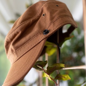 Discover our transformable hat, crafted from organic cotton and accompanied by an up-cycled leather pin.