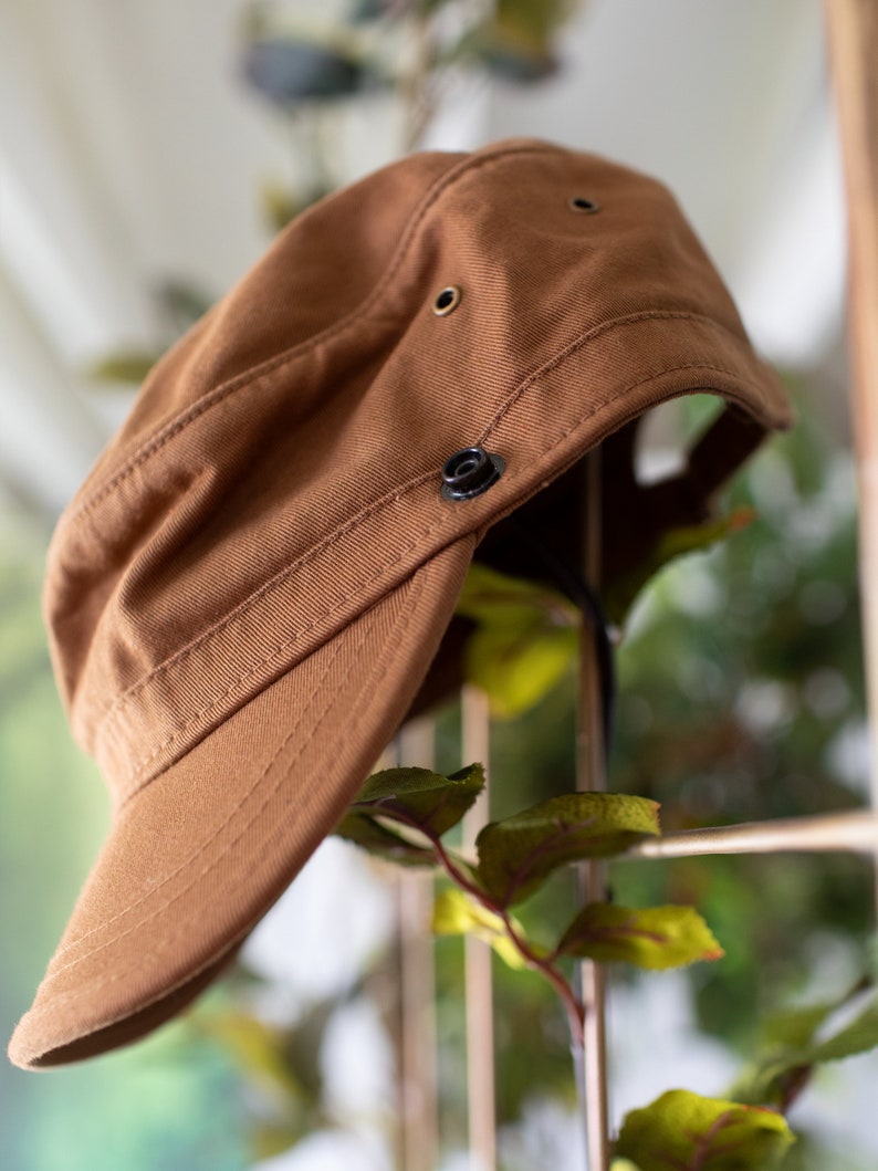 Discover our transformable hat, crafted from organic cotton and accompanied by an up-cycled leather pin.