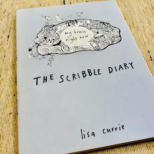 May include: A gray journal with the title "The Scribble Diary" and the text "my brain right now" above a black and white illustration of a brain. The author's name, "lisa currie", is printed at the bottom of the cover.