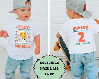 May include: White t-shirt with a pizza graphic and the text "It's My Birthday". The back of the shirt has the text "Hudson" and the number "2" in a checkered pattern. A child is wearing the shirt and holding a skateboard.