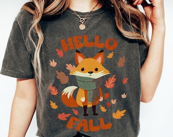 May include: A dark gray t-shirt with a cartoon fox wearing a scarf and the text "Hello Fall" in orange letters.