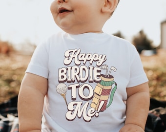 May include: White baby t-shirt featuring the text "Happy Birdie To Me!" in a retro style. The design includes a golf ball on a tee and a golf bag with clubs. The t-shirt is designed for a baby.