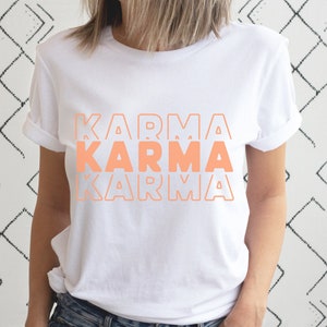 Może przedstawiać: Biała koszulka z napisem "KARMA" powt&oacute;rzonym trzy razy w układzie piętrowym, w kolorze brzoskwiniowym.