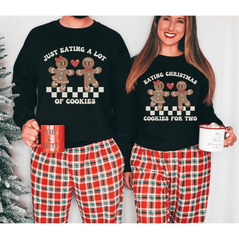 May include: A couple wearing matching black Christmas sweaters with gingerbread people and the text "Just eating a lot of cookies" and "Eating Christmas cookies for two". They are wearing red and green plaid pajamas.