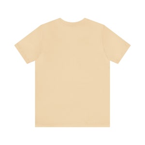 May include: A plain, light beige t-shirt with short sleeves.