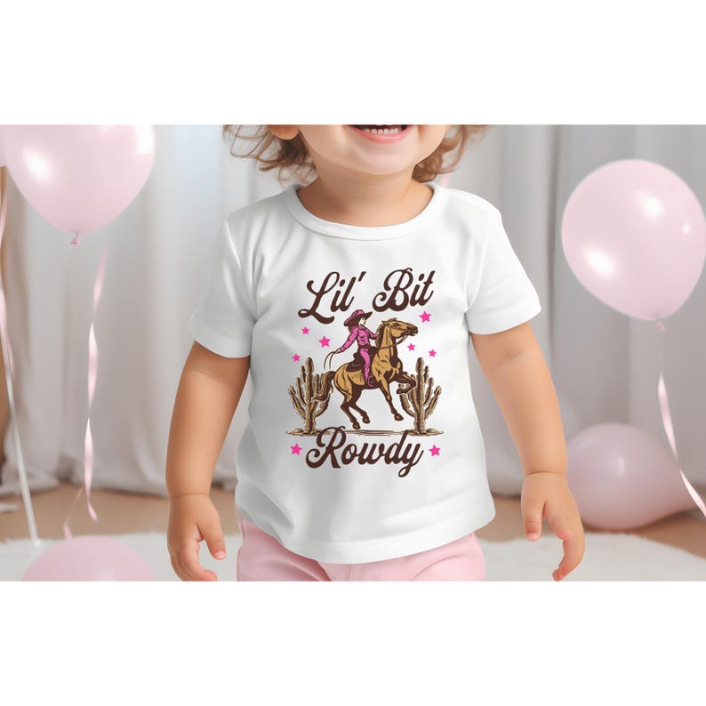 May include: White t-shirt with a brown graphic of a girl riding a horse with the text "Lil' Bit Rowdy" in brown letters.
