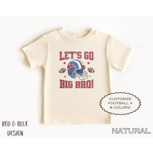 Puede incluir: Camiseta color crema con un dise&ntilde;o de f&uacute;tbol rojo y azul. El dise&ntilde;o incluye un casco de f&uacute;tbol, balones de f&uacute;tbol y el texto "LET'S GO BIG BRO!". Texto adicional: "RED & BLUE DESIGN" y "&iexcl;PERSONALIZA F&Uacute;TBOL # Y COLORES!"