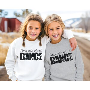 May include: Two girls wearing sweatshirts with the text "Passionate about DANCE" and a graphic of dancers. One sweatshirt is white and the other is gray.