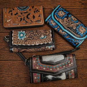 Könnte beinhalten: Vier Ledergeldbörsen mit aufwendigen floralen und geometrischen Designs. Die Geldbörsen weisen verschiedene Farben auf, darunter Braun, Schwarz, Türkis und Weiß. Eine Geldbörse hat ein Kuhfell-Panel. Jede Geldbörse hat eine andere Form und einen anderen Verschlussstil.