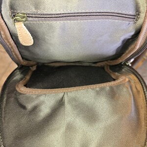 Puede incluir: Un bolso de cuero marr&oacute;n con un bolsillo con cremallera y un forro de tela marr&oacute;n. El bolso tiene una solapa que se cierra con una cremallera.