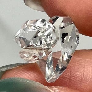 Peut inclure: Une bague transparente à facettes taillée dans un seul bloc de matériau cristallin. Le bijou présente un design géométrique angulaire composé de multiples surfaces planes qui reflètent la lumière, offrant un aspect brillant et éclatant.