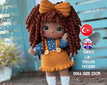 Könnte beinhalten: Häkelpuppe mit braunen Locken, einer braunen Schleife, einem blau-weiß gepunkteten Kleid und braunen Schuhen. Die Puppe ist 25 cm groß.