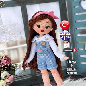 May include: Crochet doll pattern in Turkish and English. The doll is wearing a white shirt, blue overalls, and white boots. The doll has brown hair and a pink headband. The pattern is available as a PDF download.