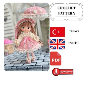 May include: A crochet doll with long brown hair, wearing a cream and pink dress with lace trim, a matching bonnet, and holding a pink umbrella with floral accents. The image includes text reading CROCHET PATTERN, TÜRKÇE, ENGLISH, PDF, and DOWNLOAD.